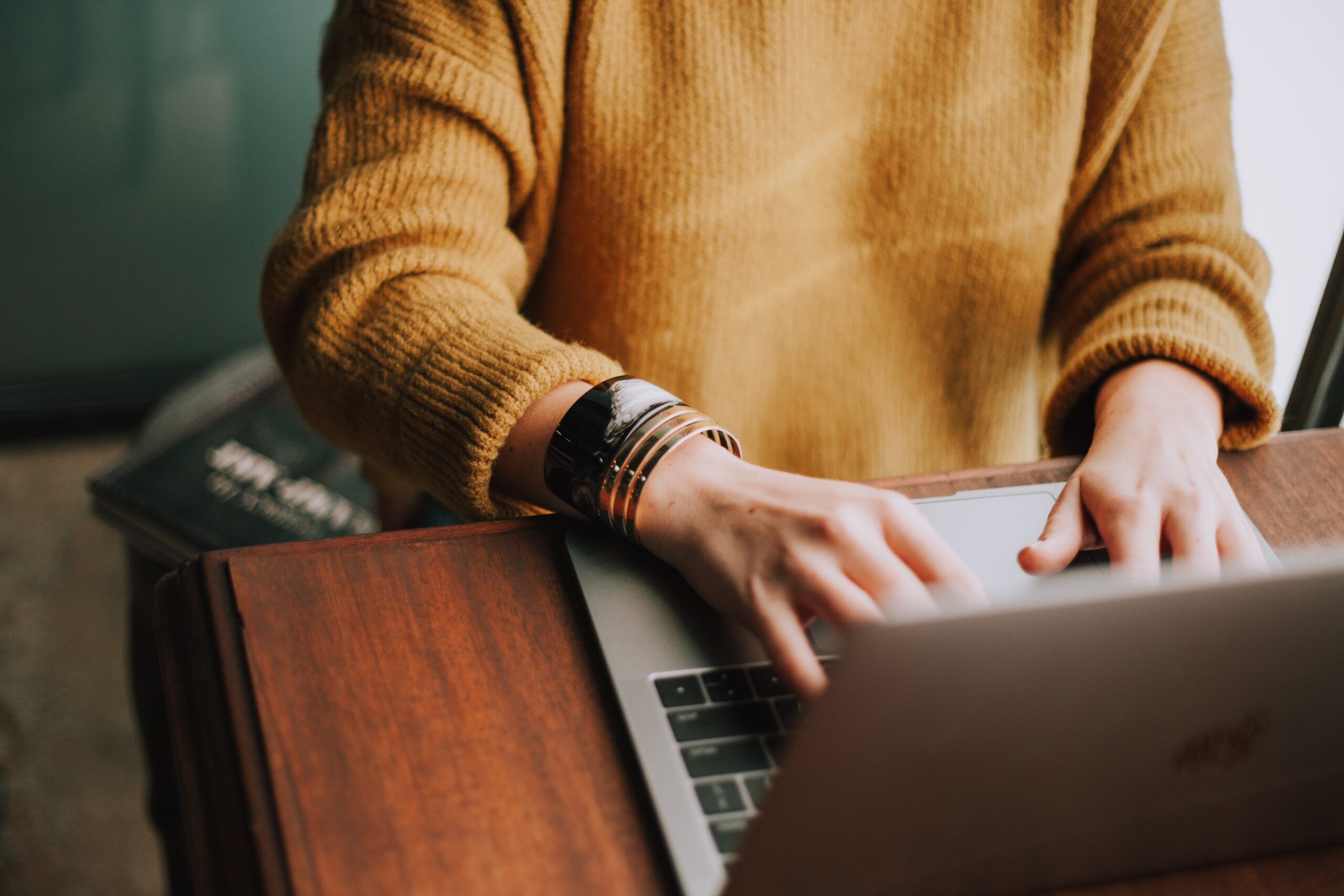 Photo of woman in yellow sweater typing at a computer.