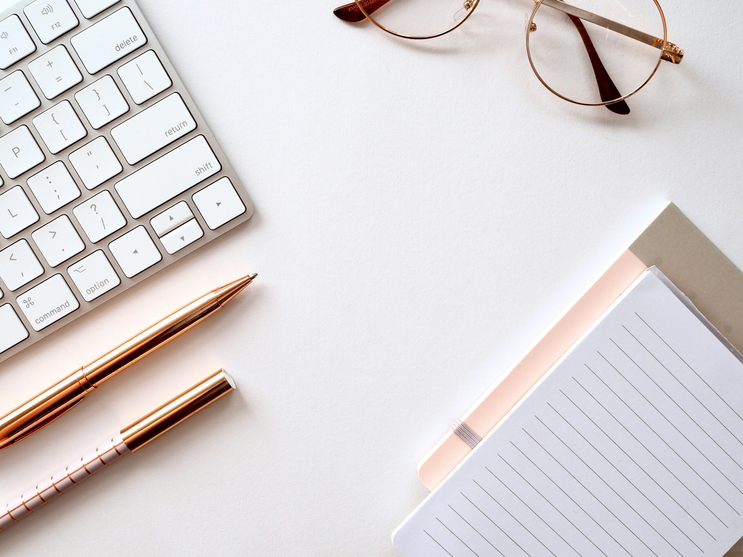 Overhead aesthetic photo of glasses, macbook, pens, and notebook.